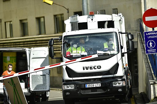 A truck with workers wearing face with masks pass through a barrier at a a public hospital, in Vitoria, northern Spain, Friday, March 13, 2020. For most people, the new COVID-19 coronavirus causes only mild or moderate symptoms, such as fever and cough, but for some, especially older adults and people with existing health problems, it can cause more severe illness, including pneumonia. (AP Photo/Alvaro Barrientos)