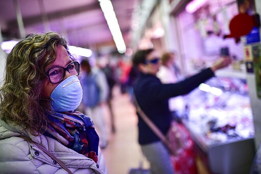 A customer wears a mask while visiting a market, in Pamplona, northern Spain, Friday, March 13, 2020. For most people, the new COVID-19 coronavirus causes only mild or moderate symptoms, such as fever and cough, but for some, especially older adults and people with existing health problems, it can cause more severe illness, including pneumonia. (AP Photo/Alvaro Barrientos)