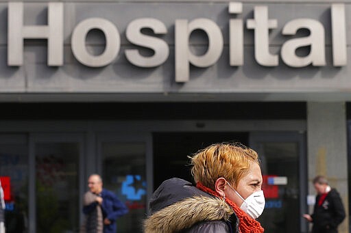 A woman wears a face mask at La Paz hospital in Madrid, Spain, Thursday, March 12, 2020. Exhibitions, conferences, sports centers and museums are closing in Madrid, including the Spanish capital's Prado Museum for the first time in eight decades. For some, especially older adults and people with existing health problems, it can cause more severe illness, including pneumonia. (AP Photo/Manu Fernandez)