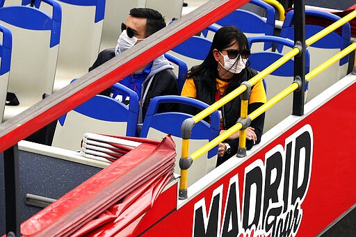 People wear face masks in a tourist bus in Madrid, Spain, Thursday, March 12, 2020. Exhibitions, conferences, sports centers and museums are closing in Madrid, including the Spanish capital's Prado Museum for the first time in eight decades. For some, especially older adults and people with existing health problems, it can cause more severe illness, including pneumonia. (AP Photo/Manu Fernandez)