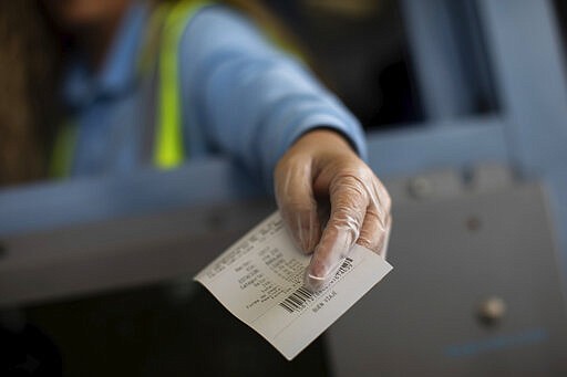 A highway toll station worker wears protective gloves while handing over a receipt, outskirts Madrid, Spain, Thursday, March 12, 2020. The vast majority of people recover from the new coronavirus. According to the World Health Organization, most people recover in about two to six weeks, depending on the severity of the illness. (AP Photo/Bernat Armangue)