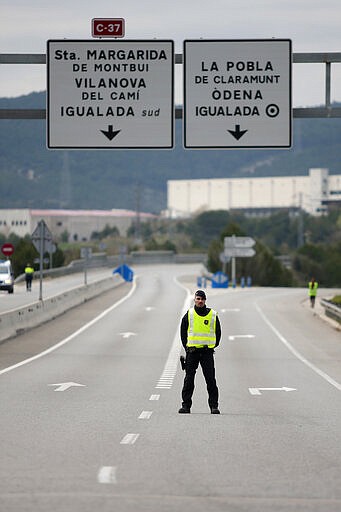 Police officer stands on the closed off road near Igualada, Spain, Friday, March 13, 2020. Over 60,000 people awoke Friday in four towns near Barcelona confined to their homes and with police blocking roads. The order by regional authorities in Catalonia is Spain's first mandatory lockdown as COVID-19 coronavirus infections increase sharply, putting a strain on health services and pressure on the government for more action. For most people, the new coronavirus causes only mild or moderate symptoms, such as fever and cough. For some, especially older adults and people with existing health problems, it can cause more severe illness, including pneumonia. (AP Photo/Joan Mateu)
