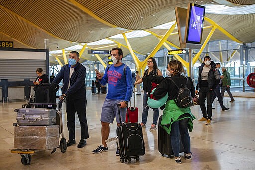 Passengers, some of them wearing masks, check flight status at Adolfo Suarez-Barajas international airport, outskirts Madrid, Spain, Thursday, March 12, 2020. The vast majority of people recover from the new coronavirus. According to the World Health Organization, most people recover in about two to six weeks, depending on the severity of the illness. (AP Photo/Bernat Armangue)