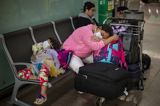 Passengers rest at the Barcelona airport, Spain, Thursday, March 12, 2020. President Donald Trump, who had downplayed the coronavirus for weeks, suddenly struck a different tone, announcing strict rules on restricting travel from much of Europe to begin this weekend. For most people, the new coronavirus causes only mild or moderate symptoms, such as fever and cough. For some, especially older adults and people with existing health problems, it can cause more severe illness, including pneumonia. (AP Photo/Emilio Morenatti)