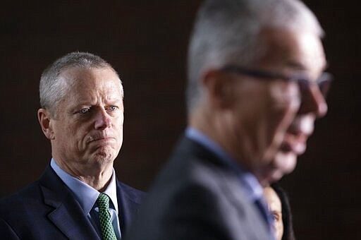 Massachusetts Gov. Charlie Baker, left, listens as CEO of the Boston Athletic Association Thomas Grilk talks about the postponement of the Boston Marathon during a news conference, Friday, March, 13, 2020, in Boston. The Marathon, which was due to be run on April 20 will be run on Monday, Sept. 14, 2020, due to concerns about the coronavirus. For most people, the new coronavirus causes only mild or moderate symptoms, such as fever and cough. For some, especially older adults and people with existing health problems, it can cause more severe illness, including pneumonia. The vast majority of people recover from the new virus. (AP Photo/Michael Dwyer)