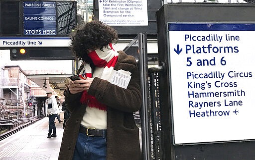 A man covers his face with a football scarf as he waits at a tube station in London, Friday, March 13, 2020. For most people, the new coronavirus causes only mild or moderate symptoms, such as fever and cough. For some, especially older adults and people with existing health problems, it can cause more severe illness, including pneumonia. (AP Photo/Kirsty Wigglesworth)