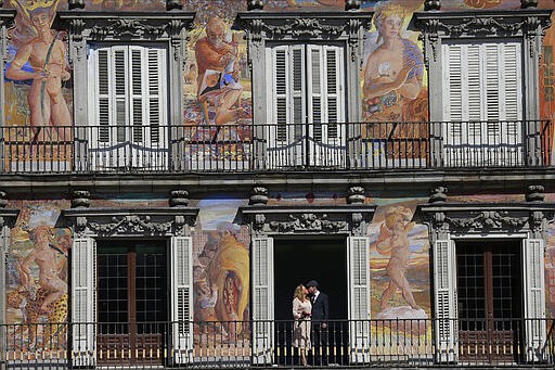 A just married couple kiss at the Mayor square in central Madrid, Spain, Wednesday, March 13, 2020.  Exhibitions, conferences, sports centers and museums are closing in Madrid, including the Spanish capital's Prado Museum for the first time in eight decades. For some, especially older adults and people with existing health problems, the COVID-19 virus can cause more severe illness, including pneumonia. (AP Photo/Manu Fernandez)