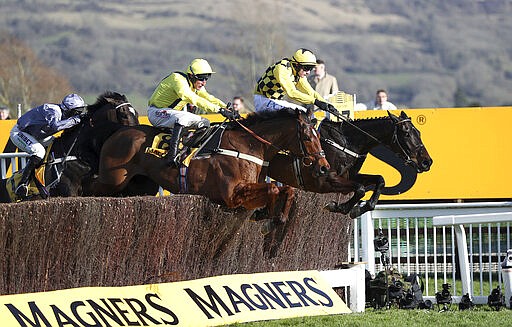 Al Boum Photo ridden by Paul Townend, right, jumps the last on the way to winning the Cheltenham Gold Cup Chase during day four of the Cheltenham Festival at Cheltenham Racecourse in Cheltenham, England, Friday, March 13, 2020. (Simon Cooper/PA via AP)