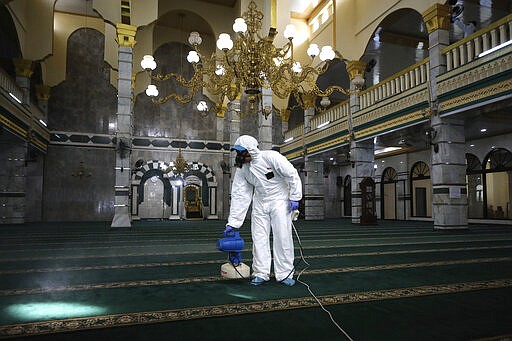 A health official sprays disinfectant in the wake of the new coronavirus outbreak ahead of the Friday prayer at a mosque in Jakarta, Indonesia, Friday, March 13, 2020. The vast majority of people recover from the new virus. According to the World Health Organization, people with mild illness recover in about two weeks, while those with more severe illness may take three to six weeks to recover. (AP Photo/Dita Alangkara)