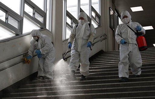 Workers wearing protective gears disinfect as a precaution against the new coronavirus at the subway station in Seoul, South Korea, Friday, March 13, 2020. For most people, the new coronavirus causes only mild or moderate symptoms, such as fever and cough. For some, especially older adults and people with existing health problems, it can cause more severe illness, including pneumonia. (AP Photo/Lee Jin-man)