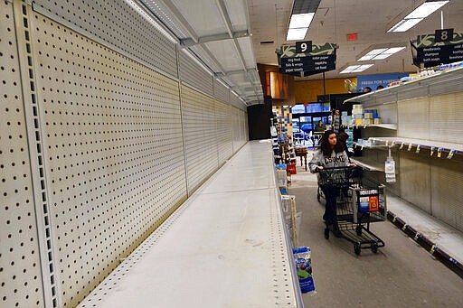 A shopper walks through an empty aisle of shelves of toilet paper  and pet foods at a local Ralphs supermarket in an attempt to stock up on supplies, Friday, March 13, 2020, in the Panorama City section of Los Angeles. Officials said Friday the Los Angeles Unified School District and San Diego school districts will close starting March 16 because of the coronavirus threat. The vast majority of people recover from the new coronavirus. According to the World Health Organization, most people recover in about two to six weeks, depending on the severity of the illness. (AP Photo/Richard Vogel)