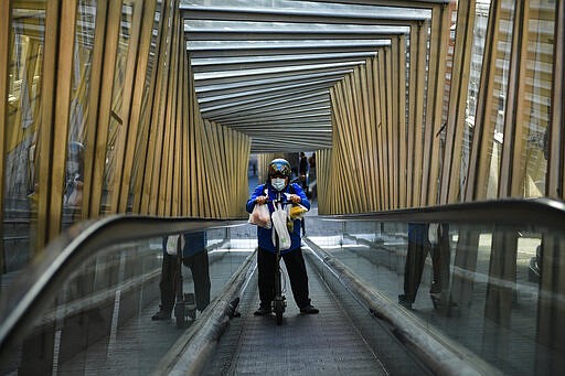 A man wearing a mask uses an escalator in the old city of Vitoria, northern Spain, Friday, March 13, 2020. For most people, the new COVID-19 coronavirus causes only mild or moderate symptoms, such as fever and cough, but for some, especially older adults and people with existing health problems, it can cause more severe illness, including pneumonia. (AP Photo/Alvaro Barrientos)