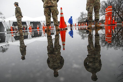 National Guard personnel stand at attention as they wait for patients to arrive for COVID-19 coronavirus testing facility at Glen Island Park, Friday, March 13, 2020, in New Rochelle, N.Y.  State officials have set up a &#147;containment area&#148; in the New York City suburb, where schools and houses of worship are closed within a 1-mile radius of a point near a synagogue where an infected person with coronavirus had attended events. State officials stress it is not a lockdown. The vast majority of people recover from the new coronavirus. According to the World  Health Organization, most people recover in about two to six weeks, depending on the severity of the illness. (AP Photo/John Minchillo)