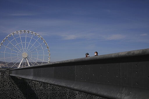 Brazilian tourists wear a mask as they visit the Mucem Museum in Marseille, southern France, Friday, March 13, 2020. For most people, the new coronavirus causes only mild or moderate symptoms. For some it can cause more severe illness. (AP Photo/