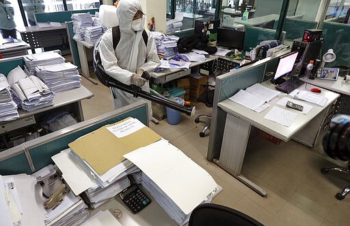 A worker wearing a protective suit disinfects the city hall in Marikina, east of Manila, Philippines on Friday, March 13, 2020. The Philippine president announced Thursday domestic travel to and from metropolitan Manila will be suspended for a month and authorized sweeping quarantines in the crowded capital to fight the new coronavirus. For most people, the new coronavirus causes only mild or moderate symptoms. For some it can cause more severe illness.(AP Photo/Aaron Favila)