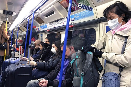 People wear masks and gloves as they travel on a tube in London, Friday, March 13, 2020. For most people, the new coronavirus causes only mild or moderate symptoms, such as fever and cough. For some, especially older adults and people with existing health problems, it can cause more severe illness, including pneumonia. (AP Photo/Kirsty Wigglesworth)