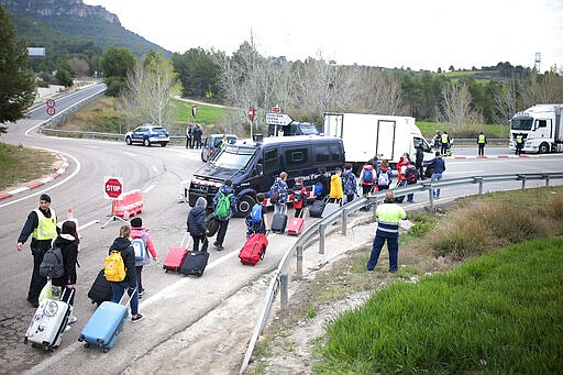 School children returning from a trip walk to change buses on a closed off road after being allowed to enter Igualada, Spain, Friday, March 13, 2020. Over 60,000 people awoke Friday in four towns near Barcelona confined to their homes and with police blocking roads. The order by regional authorities in Catalonia is Spain's first mandatory lockdown as COVID-19 coronavirus infections increase sharply, putting a strain on health services and pressure on the government for more action. For most people, the new coronavirus causes only mild or moderate symptoms, such as fever and cough. For some, especially older adults and people with existing health problems, it can cause more severe illness, including pneumonia. (AP Photo/Joan Mateu)