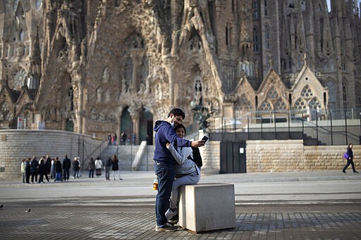 People take a selfie outside the Sagrada Familia basilica in Barcelona, Spain, Friday, March 13, 2020. The basilica closed its doors to visitors and suspend construction from Friday March 13 to prevent the spread of the new COVID-19 coronavirus. Spain, along with Italy and France, is among the countries worst hit by the virus so far in Europe. (AP Photo/Joan Mateu)