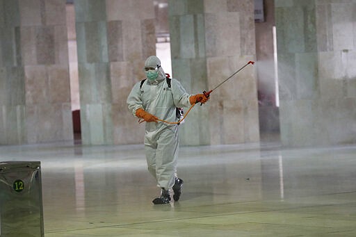 An official sprays disinfectant in the wake of the new coronavirus outbreak at Istiglal mosque in Jakarta, Indonesia, Friday, March 13, 2020. For most people the new coronavirus causes only mild or moderate symptoms, such as fever and cough. For some, especially older adults and people with existing health problems, it can cause more severe illness including pneumonia. (AP Photo/Achmad Ibrahim)