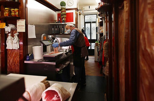 In this photo taken on Thursday, March 12, 2020, a shopkeeper works in a deli meat and cold cuts shop in Codogno, Italy. The northern Italian town that recorded Italy&#146;s first coronavirus infection has offered a virtuous example to fellow Italians, now facing an unprecedented nationwide lockdown, that by staying home, trends can reverse. Infections of the new virus have not stopped in Codogno, which still has registered the most of any of the 10 Lombardy towns Italy&#146;s original red zone, but they have slowed. For most people, the new coronavirus causes only mild or moderate symptoms. For some it can cause more severe illness. (AP Photo/Antonio Calanni)