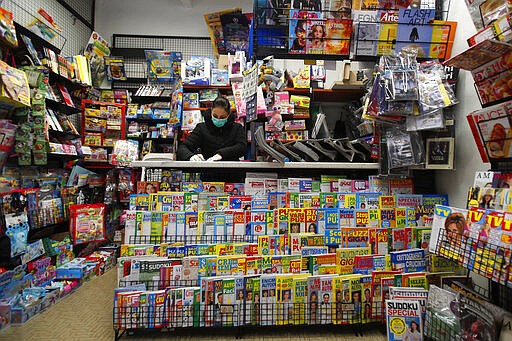 In this photo taken on Thursday, March 12, 2020, a shopkeeper wears a mask as she works in a bookshop in Codogno, Italy. The northern Italian town that recorded Italy&#146;s first coronavirus infection has offered a virtuous example to fellow Italians, now facing an unprecedented nationwide lockdown, that by staying home, trends can reverse. Infections of the new virus have not stopped in Codogno, which still has registered the most of any of the 10 Lombardy towns Italy&#146;s original red zone, but they have slowed. For most people, the new coronavirus causes only mild or moderate symptoms. For some it can cause more severe illness. (AP Photo/Antonio Calanni)