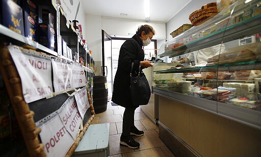 In this photo taken on Thursday, March 12, 2020, a woman buys food in a deli meat and cold cuts shop in Codogno, Italy. The northern Italian town that recorded Italy&#146;s first coronavirus infection has offered a virtuous example to fellow Italians, now facing an unprecedented nationwide lockdown, that by staying home, trends can reverse. Infections of the new virus have not stopped in Codogno, which still has registered the most of any of the 10 Lombardy towns Italy&#146;s original red zone, but they have slowed. For most people, the new coronavirus causes only mild or moderate symptoms. For some it can cause more severe illness. (AP Photo/Antonio Calanni)