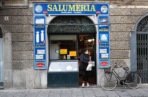 In this photo taken on Thursday, March 12, 2020, a woman gets out of a deli meat and cold cuts shop in Codogno, Italy. The northern Italian town that recorded Italy&#146;s first coronavirus infection has offered a virtuous example to fellow Italians, now facing an unprecedented nationwide lockdown, that by staying home, trends can reverse. Infections of the new virus have not stopped in Codogno, which still has registered the most of any of the 10 Lombardy towns Italy&#146;s original red zone, but they have slowed. For most people, the new coronavirus causes only mild or moderate symptoms. For some it can cause more severe illness. (AP Photo/Antonio Calanni)