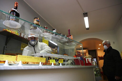 In this photo taken on Thursday, March 12, 2020, Roberto Zamproni works in his deli meat and cold cuts shop in Codogno, Italy. The northern Italian town that recorded Italy&#146;s first coronavirus infection has offered a virtuous example to fellow Italians, now facing an unprecedented nationwide lockdown, that by staying home, trends can reverse. Infections of the new virus have not stopped in Codogno, which still has registered the most of any of the 10 Lombardy towns Italy&#146;s original red zone, but they have slowed. For most people, the new coronavirus causes only mild or moderate symptoms. For some it can cause more severe illness. (AP Photo/Antonio Calanni)