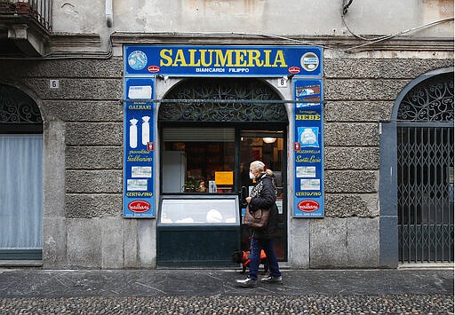 In this photo taken on Thursday, March 12, 2020, a woman walks past a deli meat and cold cuts shop in Codogno, Italy. The northern Italian town that recorded Italy&#146;s first coronavirus infection has offered a virtuous example to fellow Italians, now facing an unprecedented nationwide lockdown, that by staying home, trends can reverse. Infections of the new virus have not stopped in Codogno, which still has registered the most of any of the 10 Lombardy towns Italy&#146;s original red zone, but they have slowed. For most people, the new coronavirus causes only mild or moderate symptoms. For some it can cause more severe illness. (AP Photo/Antonio Calanni)