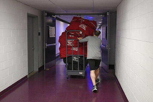 Paul Boyer, head equipment manager of The Detroit Red Wings NHL hockey team, wheels out equipment bags in the hallway of Capital One Arena, Thursday, March 12, 2020, in Washington. The Washington Capitals were to host the Red Wings Thursday evening until  the league, following the NBA&#146;s lead, suspended the season Thursday amid the coronavirus outbreak. (AP Photo/Nick Wass)