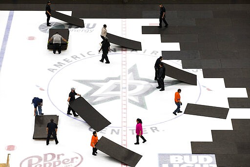 Crews cover the ice at American Airlines Center in Dallas, home of the Dallas Stars hockey team, after the NHL season was put on hold due to coronavirus, Thursday, March 12, 2020. (Ashley Landis/The Dallas Morning News via AP)