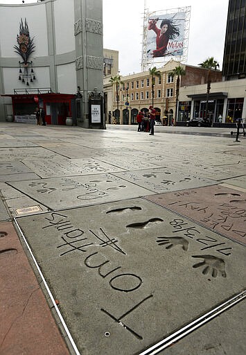 The cement inscription of actor Tom Hanks sits in the nearly empty forecourt of the TCL Chinese Theatre, Thursday, March 12, 2020, in the Hollywood section of Los Angeles. Hanks and his wife, actress-singer Rita Wilson, have tested positive for the coronavirus, the actor said in a statement Wednesday. For most people, the new coronavirus causes only mild or moderate symptoms. For some it can cause more severe illness. (AP Photo/Chris Pizzello)