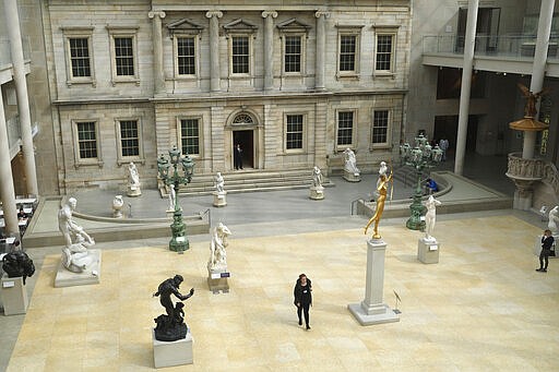 A few visitors walk through an exhibit of American art at the Metropolitan Museum of Art in New York, Tuesday, March 10, 2020. New York continued grappling  with the new coronavirus, as case numbers, school closings and other consequences grew.  (AP Photo/Seth Wenig)