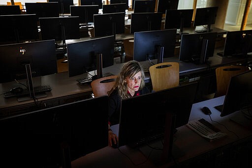 A teacher works in an empty classroom at the Pompeu Fabra university in Barcelona, Spain, Friday, March 13, 2020. Over 60,000 people have been confined to four towns in Spain's first mandatory lockdown as infections for the new coronavirus increase sharply, putting a strain on health services and pressure on the government for more action. The government has closed museums and sports centers, sent home nearly 10 million students and has asked people to work remotely, while limiting crowds at public events in high risk areas in an effort to contain the spread of COVID-19. For most people, the new coronavirus causes only mild or moderate symptoms, such as fever and cough. (AP Photo/Emilio Morenatti)