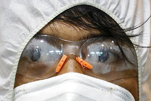 Mist is seen on the googles of a worker wearing a protective suit as he disinfects the city hall of Marikina, in Manila, Philippines on Friday, March 13, 2020. The Philippine president announced Thursday domestic travel to and from metropolitan Manila will be suspended for a month and authorized sweeping quarantines in the crowded capital to fight the new coronavirus. For most people, the new coronavirus causes only mild or moderate symptoms. For some it can cause more severe illness.(AP Photo/Aaron Favila)