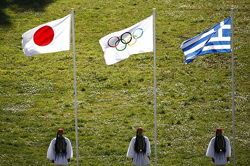 FILE - In this Thursday, March 12, 2020, file photo, Greek Evzones guards stand next to Japan, Olympic and Greece flags, from left, during the flame lighting ceremony at the closed Ancient Olympia site, birthplace of the ancient Olympics in southern Greece. U.S. President Donald Trump's suggestion to postpone the Tokyo Olympics for a year because of the spreading virus was immediately shot down by Japan's Olympic Minister Seiko Hashimoto. (AP Photo/Yorgos Karahalis, File)