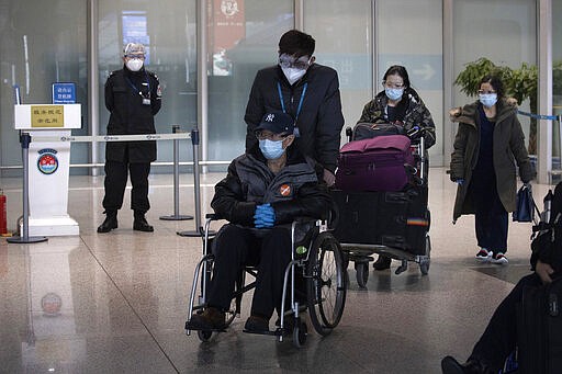 In this March 12, 2020, photo, travelers leave the international arrival exit at the Capital International Airport terminal 3 in Beijing. As the number of new cases dwindles in China and multiplies abroad, the country once feared as the source of the COVID-19 outbreak is now worried about importing cases from abroad. China hasn't imposed any travel bans, but Beijing said this week that all people arriving from overseas would have to self-quarantine for 14 days. (AP Photo/Ng Han Guan)