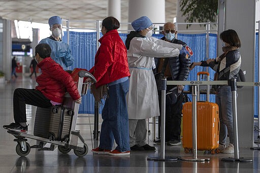 In this March 12, 2020, photo, health workers screen people entering the Capital International Airport terminal 3 in Beijing.  As a virus pandemic spreads globally, China and other parts of Asia are scrambling to prevent it from coming back to where it broke out. Everyone arriving in Beijing must be quarantined for 14 days, and South Korea is screening arriving passengers from more countries as the number of cases rises across Europe. (AP Photo/Ng Han Guan)