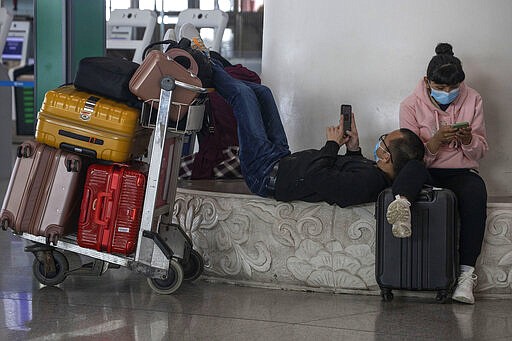 In this March 12, 2020, photo, travelers wait for their flight at the Capital International Airport terminal 3 in Beijing. As a virus pandemic spreads globally, China and other parts of Asia are scrambling to prevent it from coming back to where it broke out. Everyone arriving in Beijing must be quarantined for 14 days, and South Korea is screening arriving passengers from more countries as the number of cases rises across Europe.(AP Photo/Ng Han Guan)