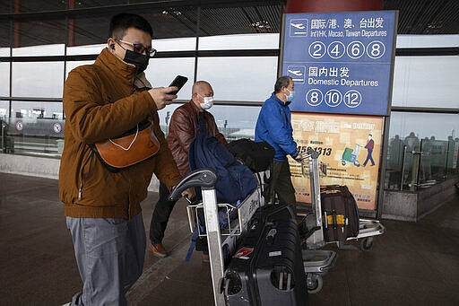 In this March 12, 2020, photo, travelers walk outside the Capital International Airport terminal 3 in Beijing. As a virus pandemic spreads globally, China and other parts of Asia are scrambling to prevent it from coming back to where it broke out. Everyone arriving in Beijing must be quarantined for 14 days, and South Korea is screening arriving passengers from more countries as the number of cases rises across Europe.(AP Photo/Ng Han Guan)