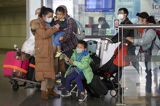 In this March 12, 2020, photo, travelers walk out from the international arrival exit at the Capital International Airport terminal 3 in Beijing. As the number of new cases dwindles in China and multiplies abroad, the country once feared as the source of the COVID-19 outbreak is now worried about importing cases from abroad. China hasn't imposed any travel bans, but Beijing said this week that all people arriving from overseas would have to self-quarantine for 14 days.  (AP Photo/Ng Han Guan)