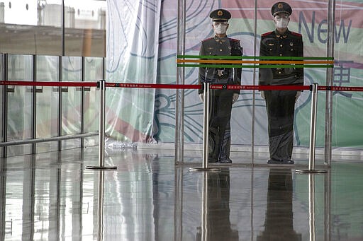 In this March 12, 2020, photo, Chinese paramilitary policemen stand on duty behind a barrier at the Capital International Airport terminal 3 in Beijing. As the number of new cases dwindles in China and multiplies abroad, the country once feared as the source of the COVID-19 outbreak is now worried about importing cases from abroad. China hasn't imposed any travel bans, but Beijing said this week that all people arriving from overseas would have to self-quarantine for 14 days. (AP Photo/Ng Han Guan)