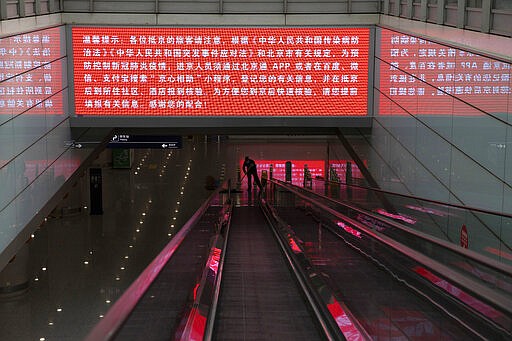 In this March 12, 2020, photo, a worker mops the area under a screening showing China's regulations related to the coronavirus outbreak at the Capital International Airport terminal 3 in Beijing. As a virus pandemic spreads globally, China and other parts of Asia are scrambling to prevent it from coming back to where it broke out. Everyone arriving in Beijing must be quarantined for 14 days, and South Korea is screening arriving passengers from more countries as the number of cases rises across Europe.(AP Photo/Ng Han Guan)