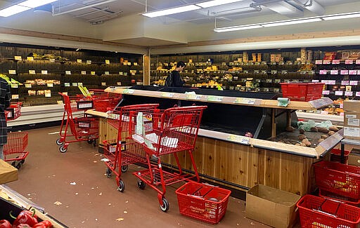 A man checks his cellphone near shelves at a New York City Trader Joe's market in disarray, Thursday, March 12, 2020. Coronavirus fears have some New Yorkers stocking up on essentials as uncertainty grows over what would be available and whether they would be able to leave home to get what they need. (Sarah Vaynerman via AP)