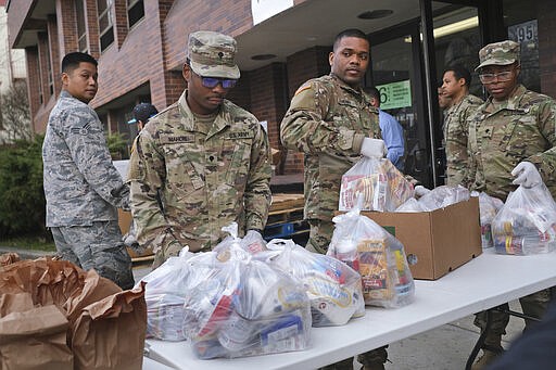 Members of the New York National Guard help to organize and distribute food to families on free or reduced school lunch programs in New Rochelle, N.Y., Thursday, March 12, 2020.  State officials have set up a &#147;containment area&#148; in the New York City suburb, where schools and houses of worship are closed within a 1-mile radius of a point near a synagogue where an infected person with coronavirus had attended events. State officials stress it is not a lockdown. The vast majority of people recover from the new coronavirus. According to the World  Health Organization, most people recover in about two to six weeks, depending on the severity of the illness.  (AP Photo/Seth Wenig)