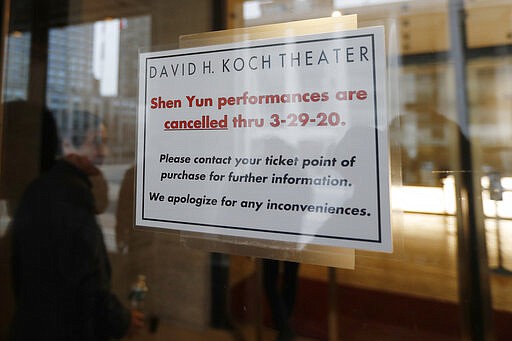 A sign on the door of the David H. Koch Theater at Lincoln Center Thursday, March 12, 2020, announces the cancellation of Shen Yun performances through March 29, in New York. Nearly all of Lincoln Center's performance spaces closed their doors after New York Gov. Andrew Cuomo announced a temporary statewide ban on gatherings of more than 500 people. For most people the new coronavirus causes only mild or moderate symptoms, such as fever and cough. For some, especially older adults and people with existing health problems, it can cause more severe illness including pneumonia. (AP Photo/Kathy Willens)