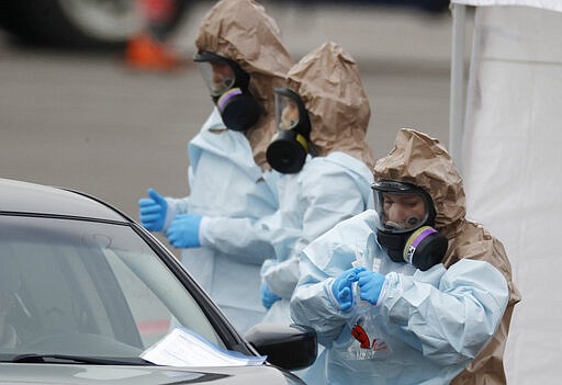 Colorado National Guard medical personnel perform coronavirus test on a motorist at a drive-through testing site outside the Denver Coliseum Saturday, March 14, 2020, in Denver. Officials planned to administer 150 tests but the line of vehicles wrapped around three city blocks. For most people, the new coronavirus causes only mild or moderate symptoms. For some it can cause more severe illness. (AP Photo/David Zalubowski)