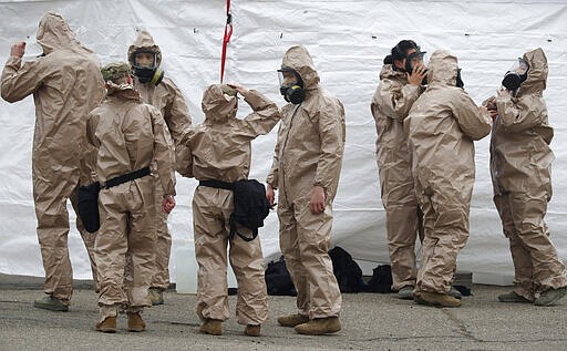 Colorado National Guard medical personnel suit up to perform coronavirus tests on motorists at a drive-through testing site outside the Denver Coliseum Saturday, March 14, 2020, in Denver. Officials planned to administer 150 tests but the line of vehicles wrapped around three city blocks. For most people, the new coronavirus causes only mild or moderate symptoms. For some it can cause more severe illness. (AP Photo/David Zalubowski)