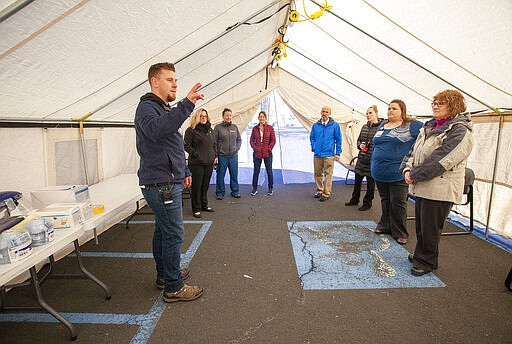 Director of Safety and Security Derec Styer, left, talks to employees during a training session on Thursday, March 12, 2020, at Gritman Medical Center in Moscow, Idaho. The training allowed employees to practicing setting up a tent that can be used for drive-up non-emergency screening for COVID-19 coronavirus. (Geoff Crimmins/Moscow-Pullman Daily News via AP)