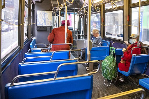 A woman wears a face mask as she rides the M42 bus crosstown, Friday, March 13, 2020, in New York. New York has more than 400 confirmed cases of COVID-19, the disease caused by the virus. For most people, the new coronavirus causes only mild or moderate symptoms, such as fever and cough. For some, especially older adults and people with existing health problems, it can cause more severe illness, including pneumonia, and death. (AP Photo/Mary Altaffer)